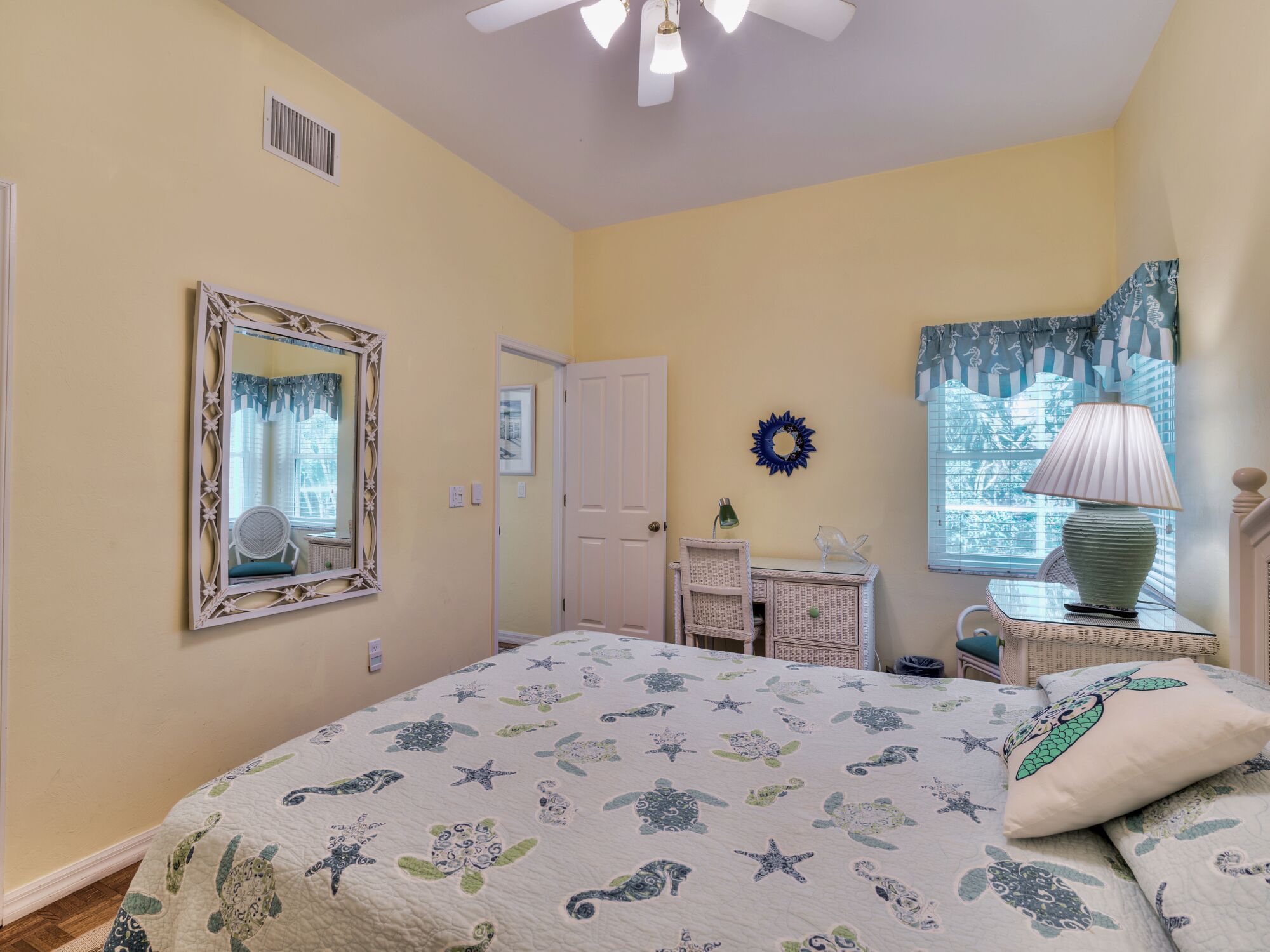 A bedroom with a bed, dresser, chair, and a window with curtains.