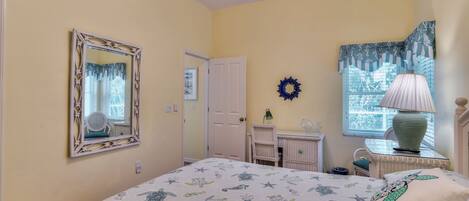 A bedroom with a bed, dresser, chair, and a window with curtains.