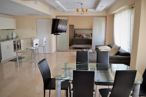 A modern living room with a glass dining table, black chairs, a sofa, and a TV mounted on the wall. - Carlyle Art Deco Residence on South Beach Ocean Drive Al Pacino would stay here! (Miami Beach)