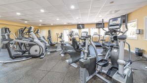 Une salle de sport équipée de divers appareils d’exercice, dotée d’un sol carrelé et d’un plafond avec des luminaires encastrés.