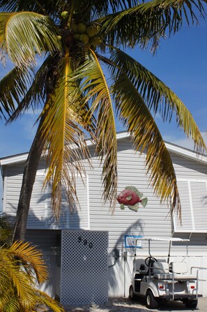 A white building with a mural of a fish, a golf cart, and a palm tree. - Dock, Htd 80' Pool, Deep Channel, 15 Min To Key West  (Cudjoe Key)