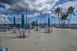 An outdoor seating area with tables and chairs, umbrellas, and a view of the ocean.
