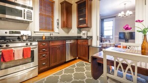 A kitchen with wooden cabinets, a stainless steel stove, and a coffee maker. - Elegant 3 Bed Apt ★ ★ ★ ★ ★ Mins to Manhattan (Hoboken)