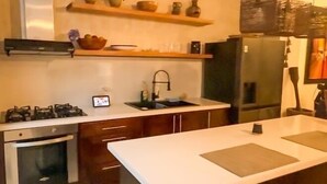 A modern kitchen with wooden cabinets, a central island, and a built-in stove. - Extraordinary  Retreat In Cartagena. Casa Kava (Cartagena)