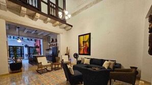 A spacious living area with a patterned floor, a dark-colored sofa set, and a dining area with chairs and a table. - Extraordinary  Retreat In Cartagena. Casa Kava (Cartagena)