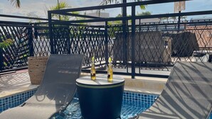 A pool area with lounge chairs and a small table, surrounded by a fence and palm trees. - Extraordinary  Retreat In Cartagena. Casa Kava (Cartagena)