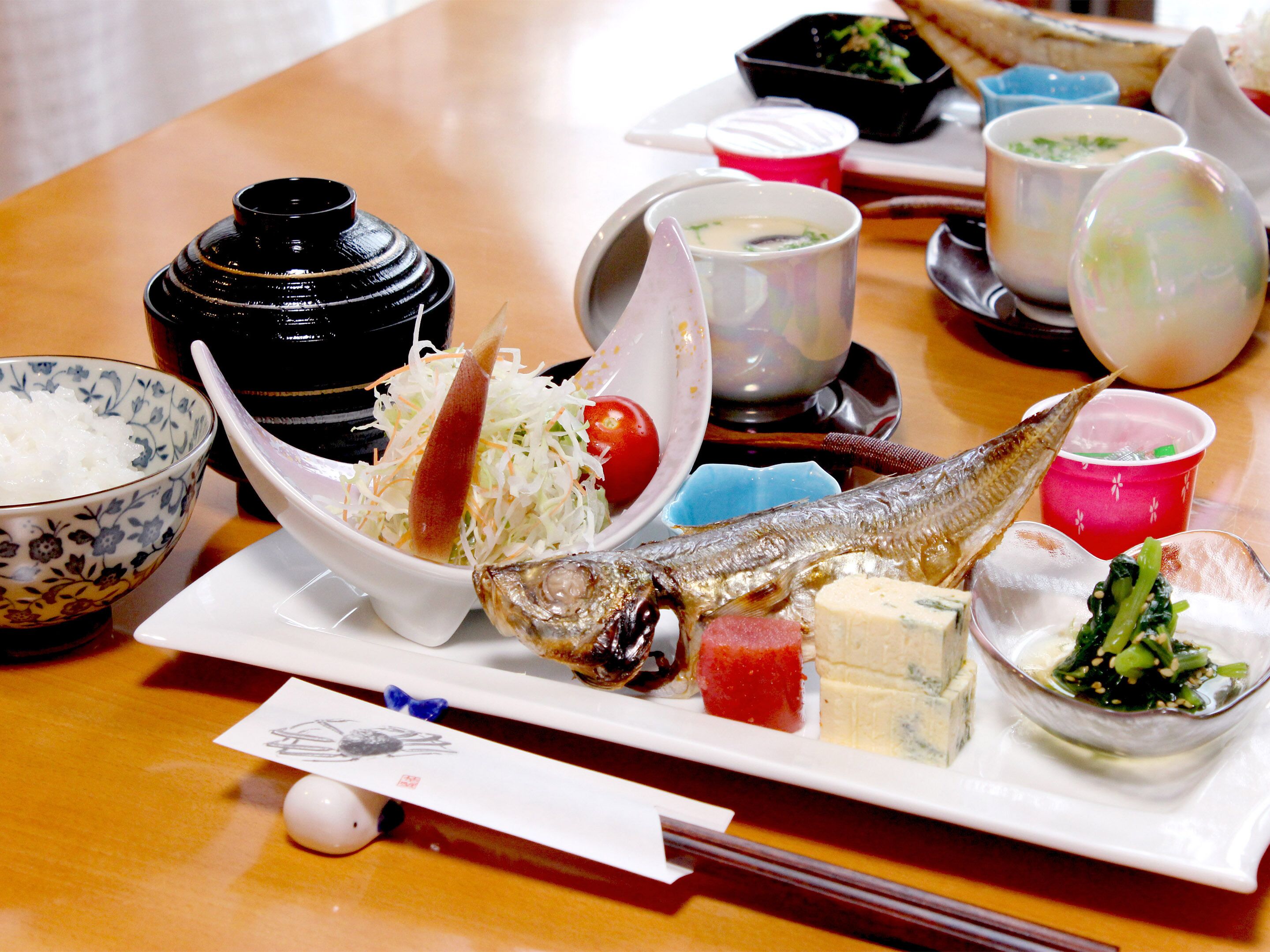 A table with various dishes including fish, rice, and vegetables.