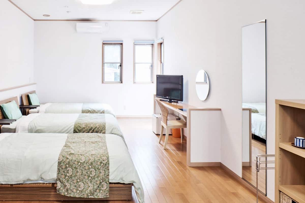 A hotel room with two beds, a TV, a desk, and a mirror.