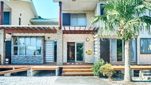 A two-story building with a stone facade, large windows, and a pergola. - Mantenbo (Hachijo)