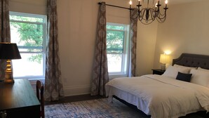 A bedroom with a bed, a nightstand, a lamp, a chair, and a window with curtains. - Beautiful 4Br downtown garden house. Sleeps 12 (Toronto)
