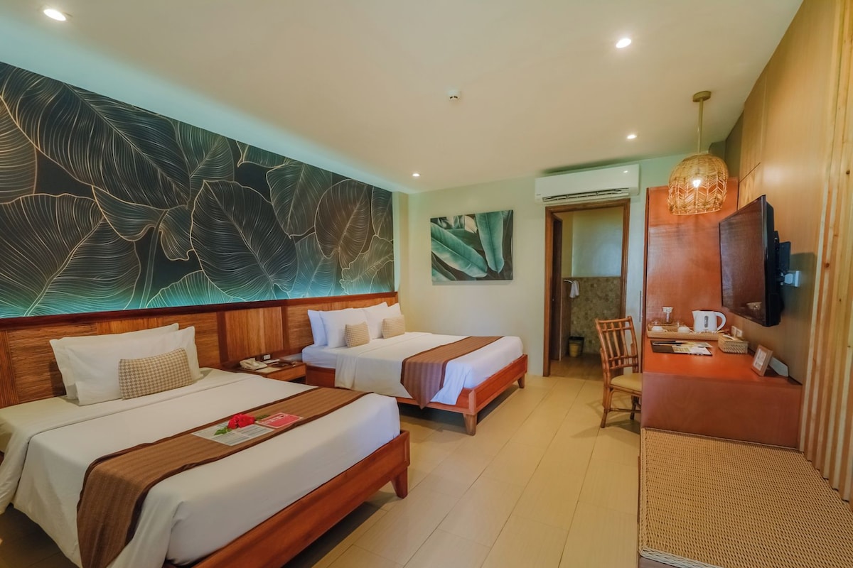 A hotel room with two beds, a TV, a desk with a chair, and artwork on the walls.