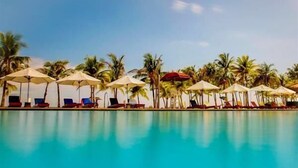 A poolside area with lounge chairs and umbrellas, surrounded by palm trees. - Bohol Beach Club (Panglao)
