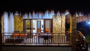 A stone building with a balcony, a table, and chairs. - Bohol Beach Club (Panglao)