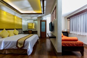 A hotel room with a large bed, a smaller bed, a desk with a chair, a television, and a window with curtains. - Bohol Beach Club (Panglao)