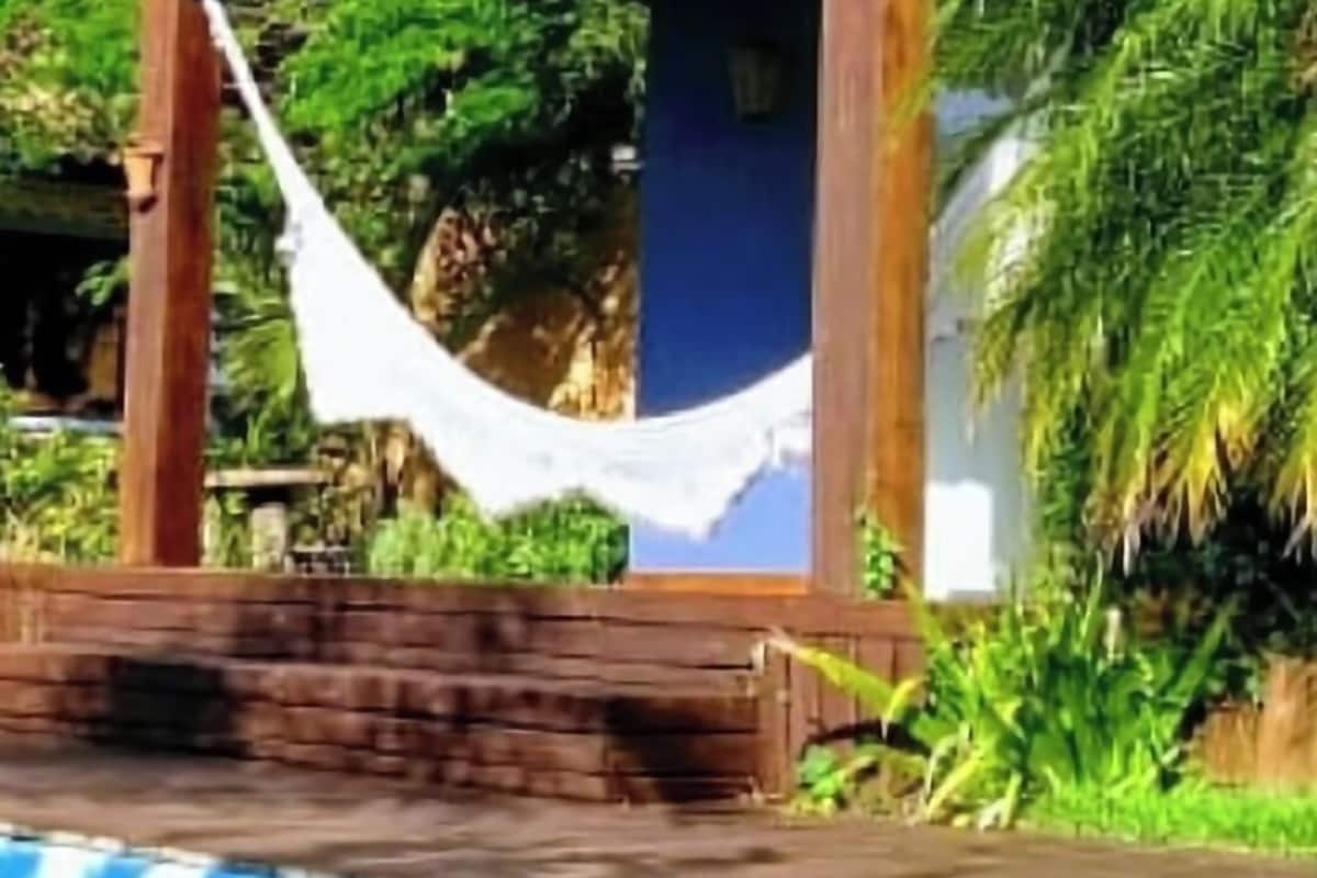 Een zwembadgedeelte met een houten pergola en een hangmat.