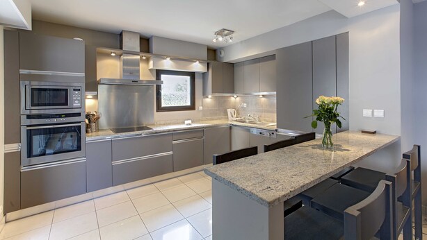 Una cucina moderna con elettrodomestici in acciaio inossidabile, un piano di lavoro in granito e un'isola integrata con posti a sedere al bancone.