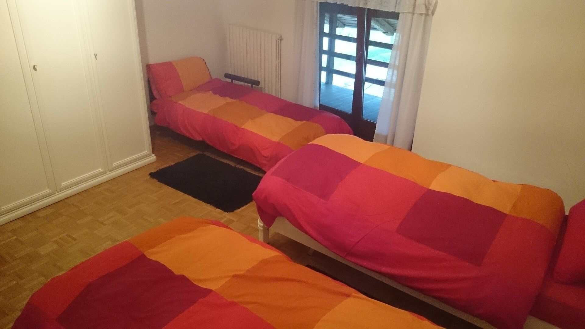 Un dormitorio con dos camas individuales, un radiador y una ventana con cortinas.