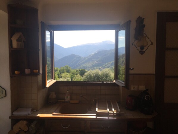 A kitchen with a window view of a mountainous landscape.