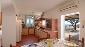 Una cocina con horno empotrado, lavamanos y comedor con mesa dispuesta para cuatro.