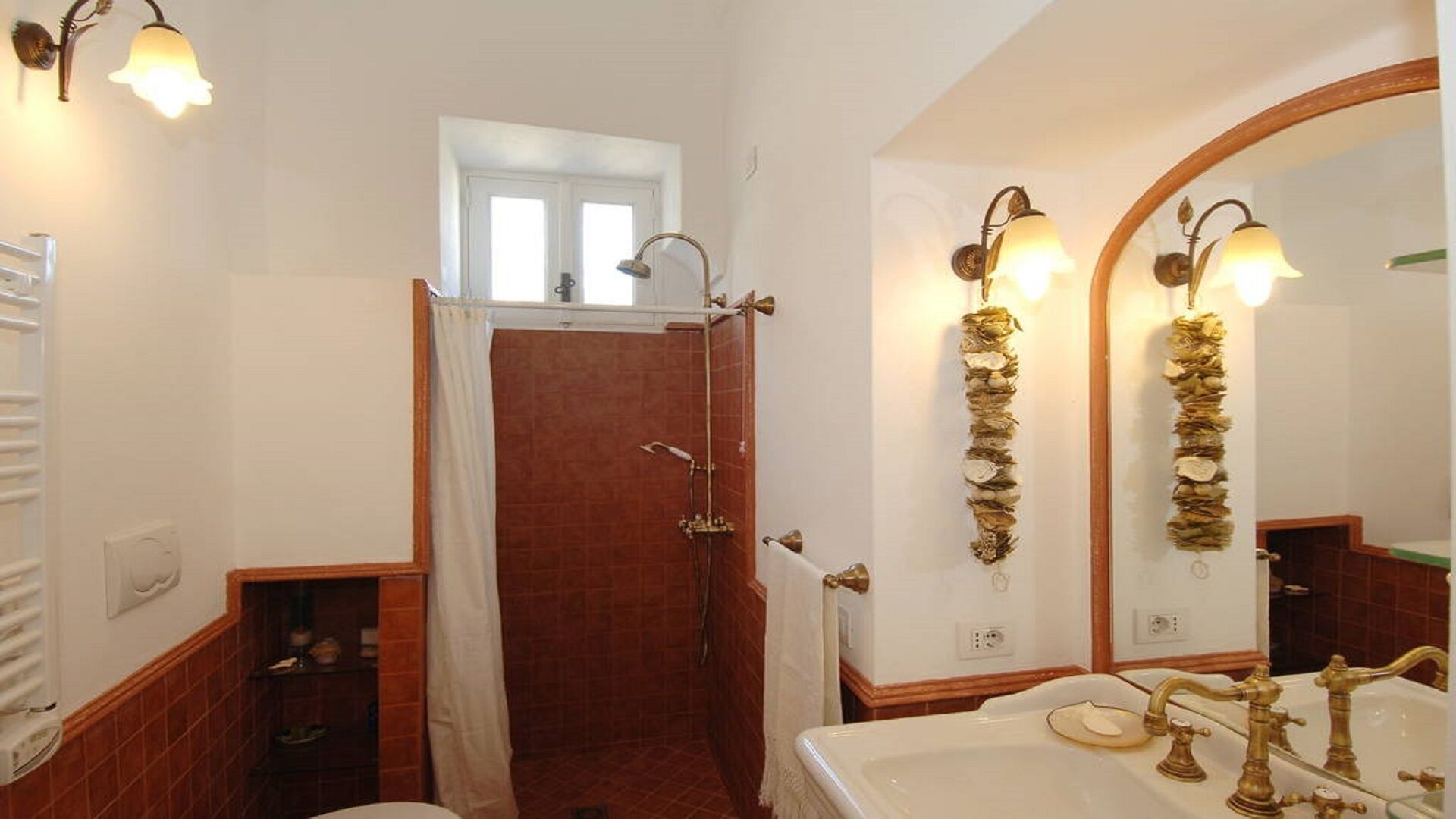 A bathroom with a shower, a sink with gold fixtures, and wall-mounted lights.