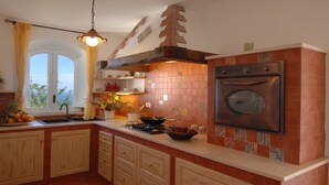 Una cocina con armarios de madera, estufa, horno y ventana con vistas.