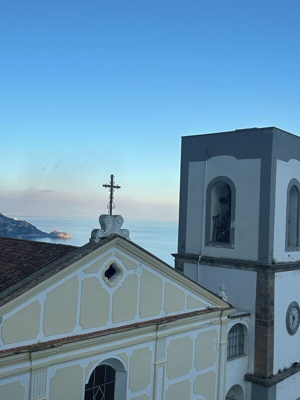 A building with a bell tower and a cross on top, overlooking a body of water.