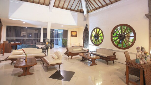 A spacious lobby with high ceilings, a large fan, and a seating area with sofas and a coffee table.