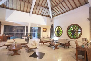 Eine geräumige Lobby mit hohen Decken, einem großen Ventilator und einer Sitzecke mit Sofas und einem Couchtisch.