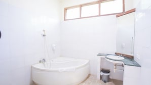 A bathroom with a bathtub, sink, and window.