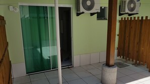 A room with a green door, two wall-mounted air conditioning units, a concrete pillar, and a wooden fence. - Residencial Floripamar I (Florianópolis)