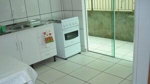A clean, white kitchen with a stove, sink, and cabinets. - Residencial Floripamar I (Florianópolis)