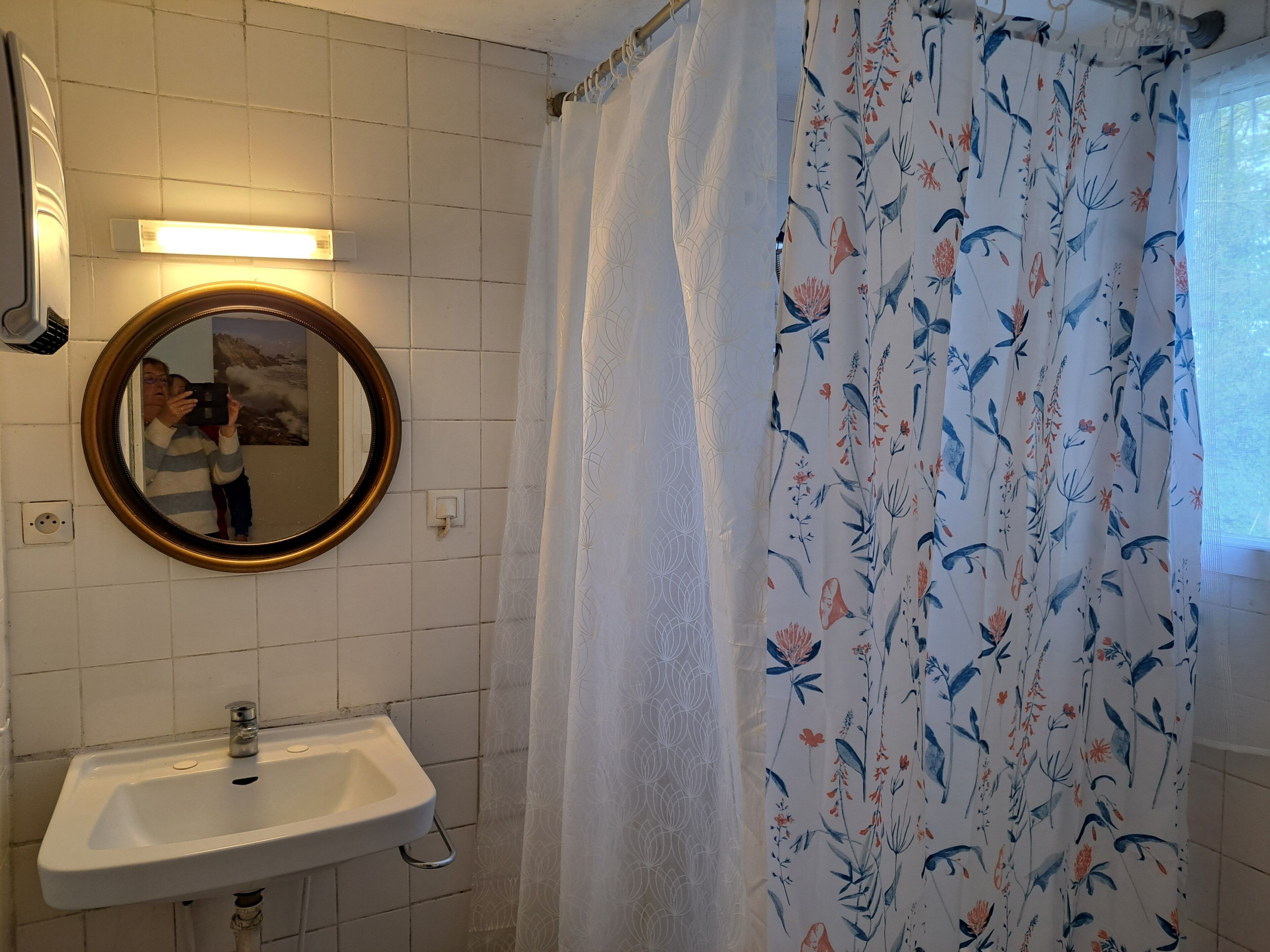 A bathroom with a sink, mirror, and floral shower curtain.