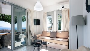 A modern living room with a sofa, a TV, and a dining area with chairs and a table.