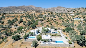 A coastal resort with multiple villas, a swimming pool, and a view of the surrounding hills.