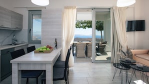 A modern kitchen with a dining area, a sofa, and a TV.