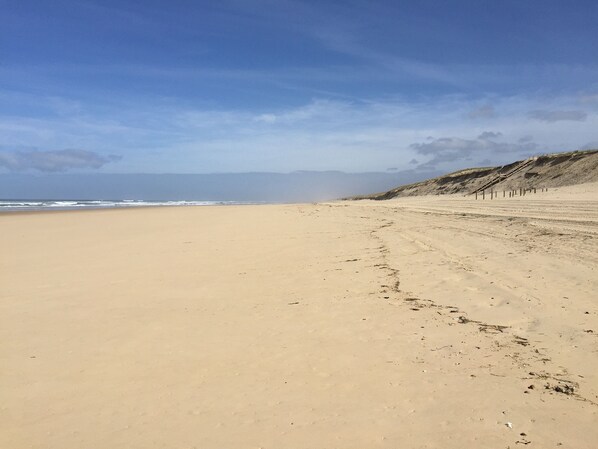 A wide, sandy beach with gentle waves and a clear sky.