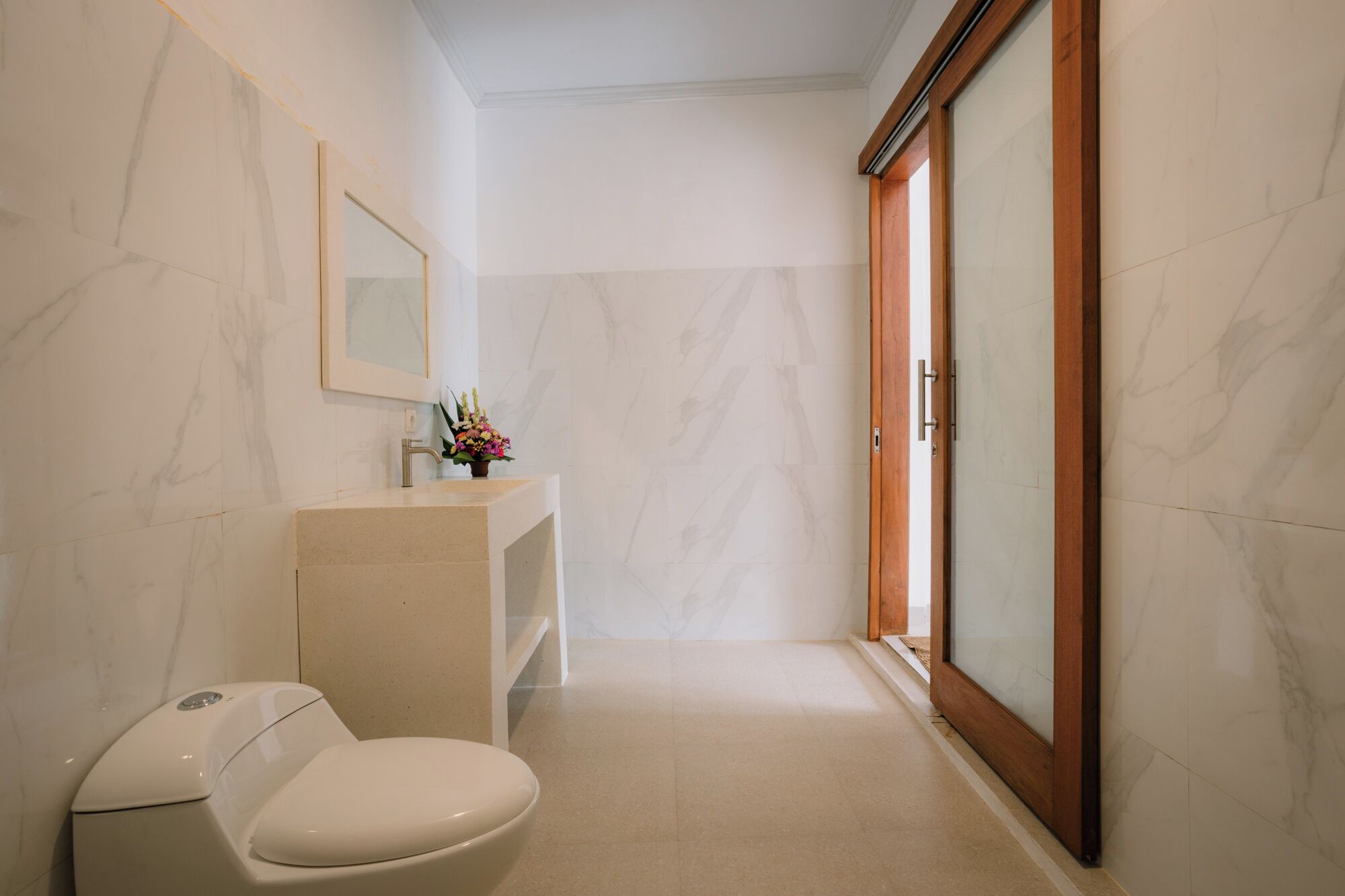 A bathroom with a toilet, sink, and mirror.