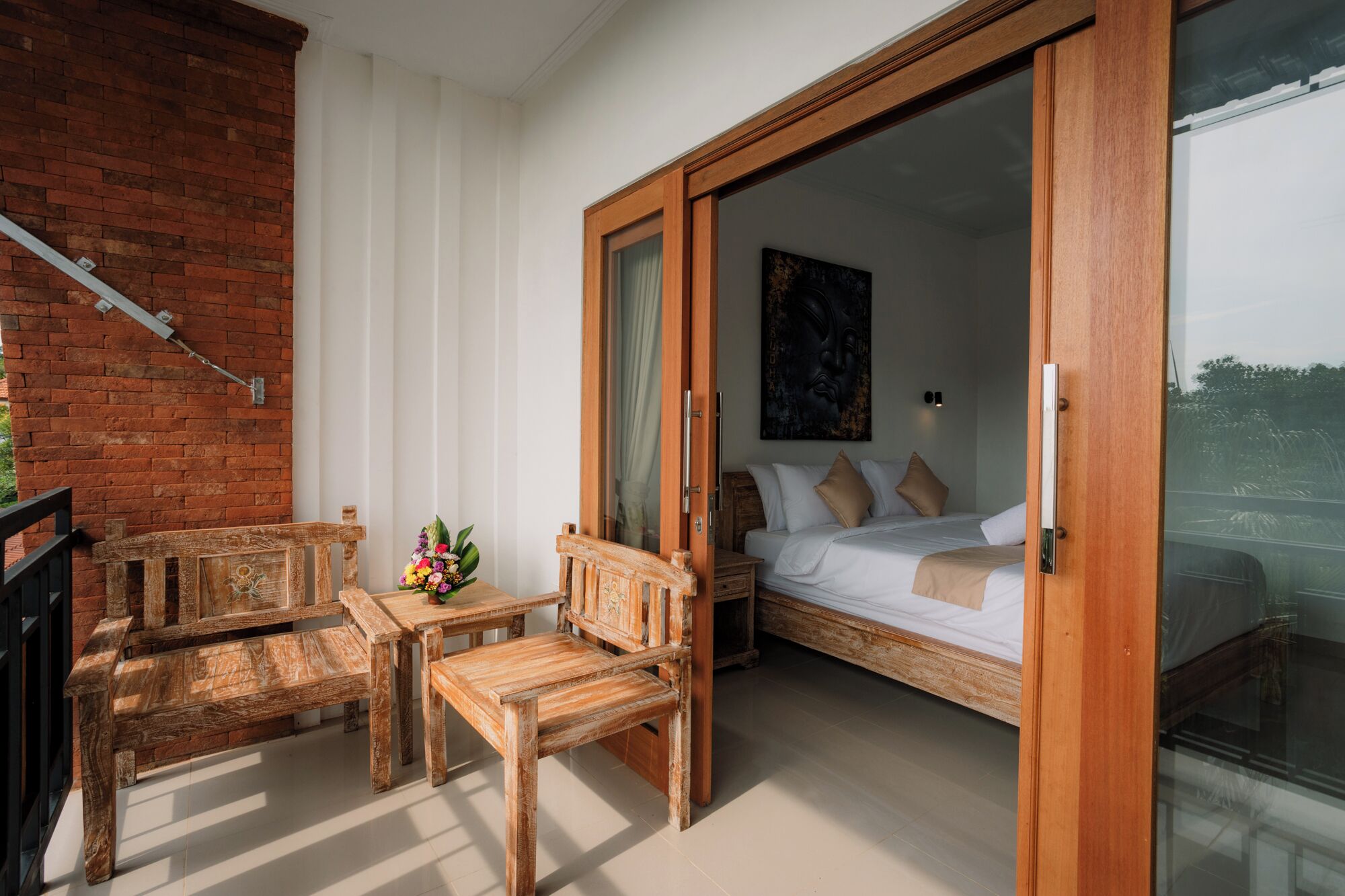 A room with a bed, a wooden bench, and a table with a floral arrangement.