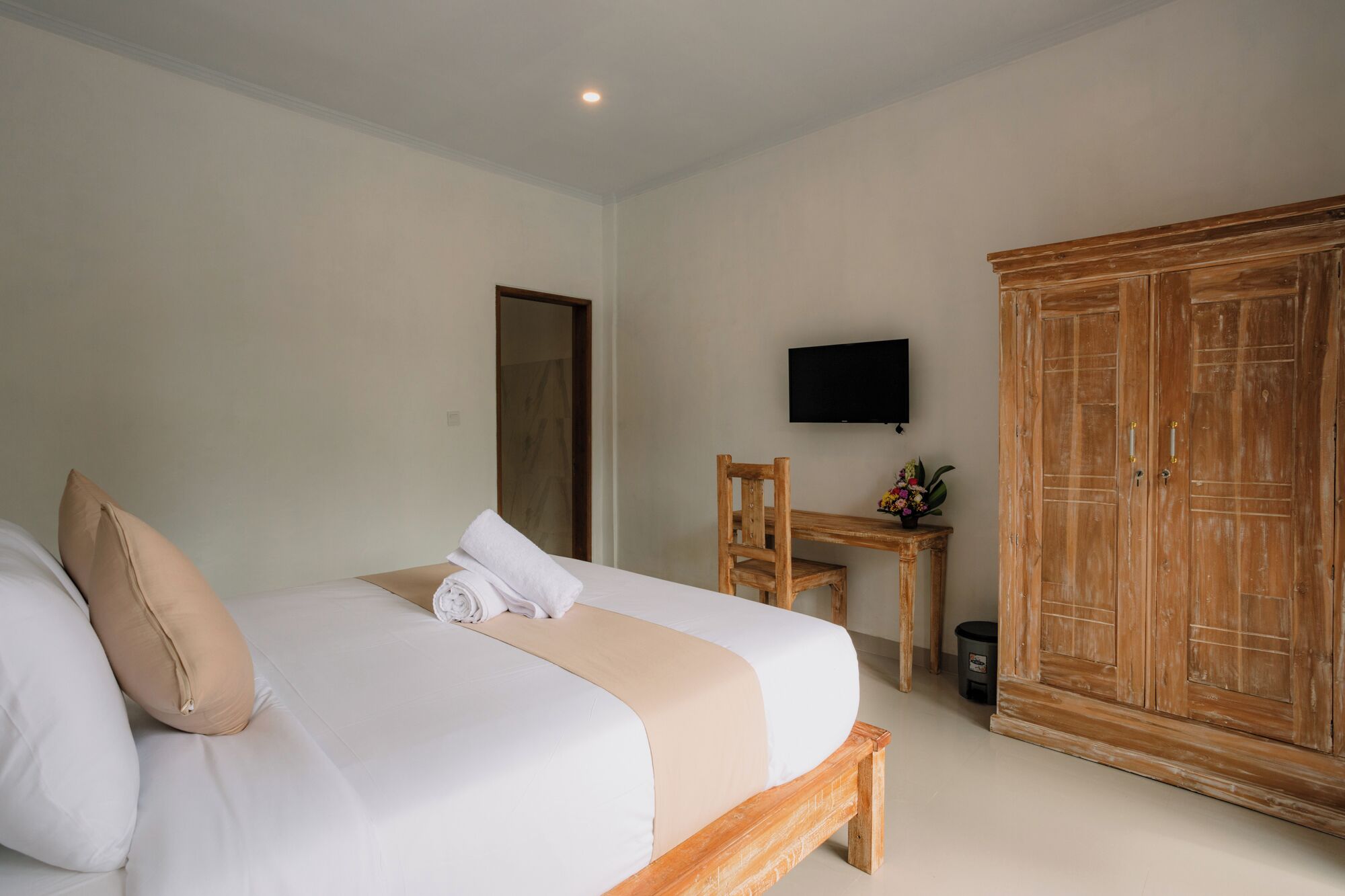 Ein Hotelzimmer mit einem Bett, einem Holzschrank, einem Schreibtisch mit Stuhl und einem an der Wand befestigten Fernseher.
