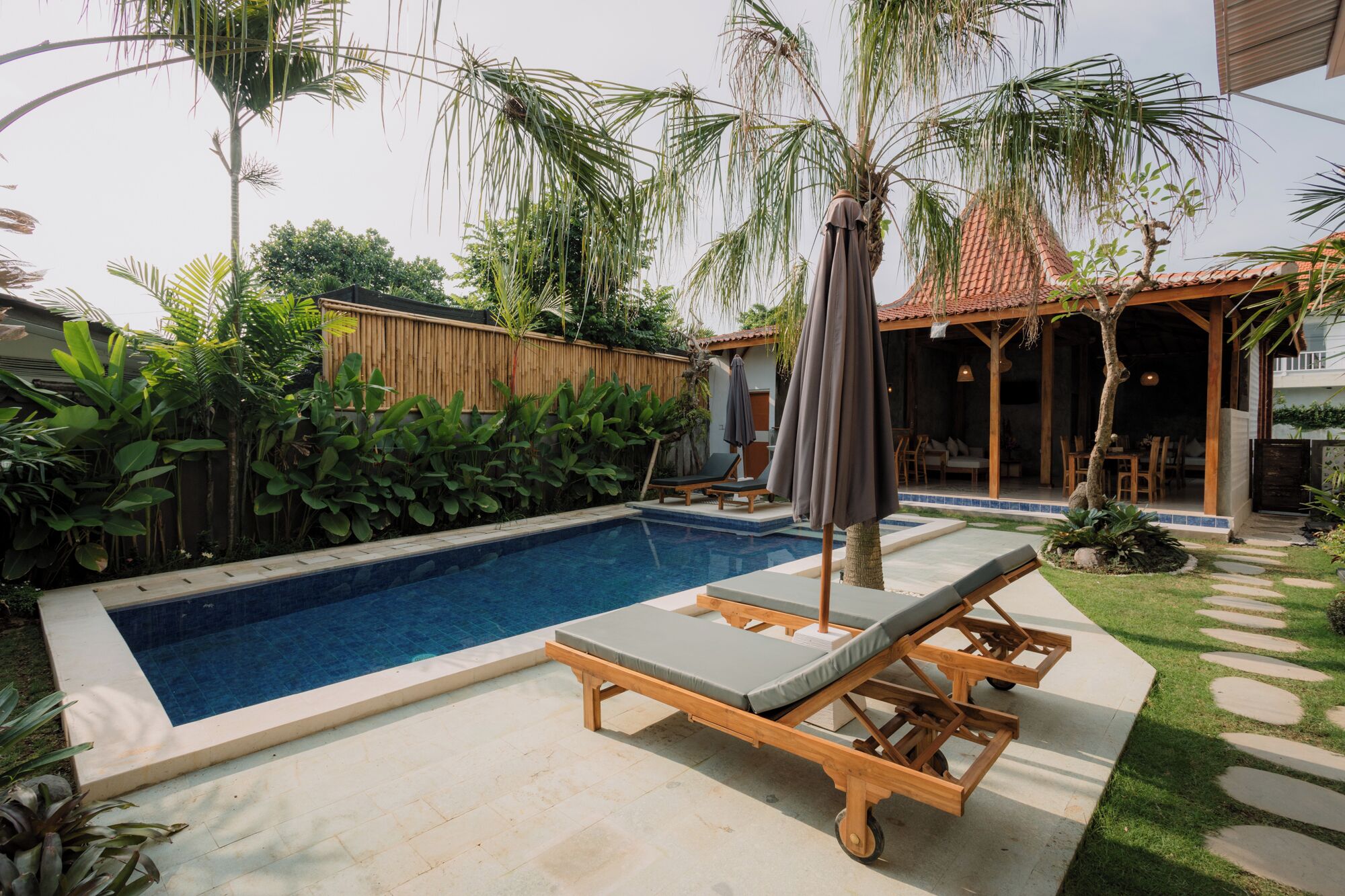 A swimming pool with lounge chairs and a covered seating area.