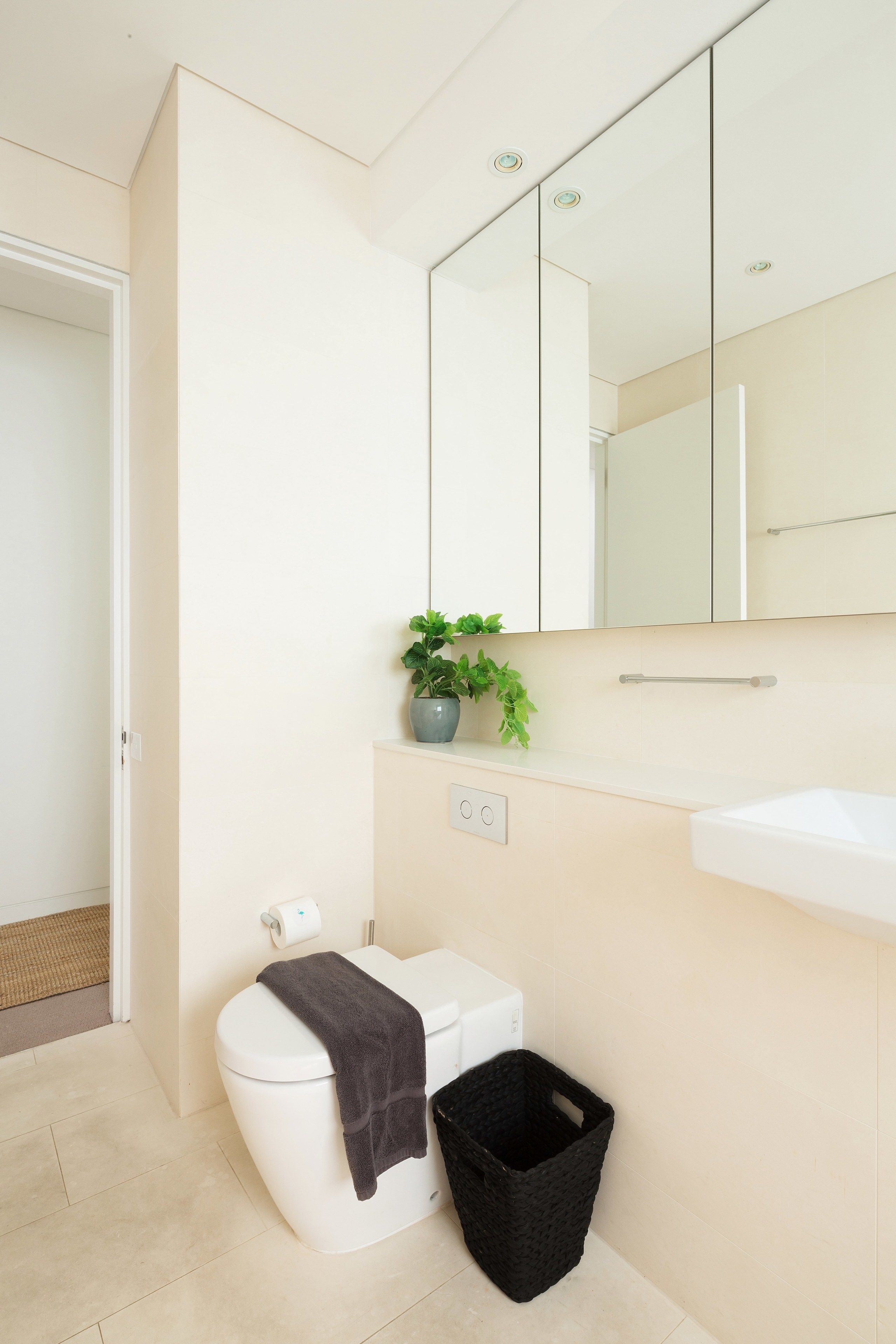 A modern bathroom with a toilet, sink, and mirror.