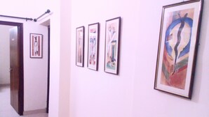 A hallway with four framed artworks on the wall. - Jo Rooms (Bidhannagar)