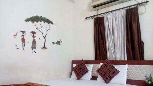 A hotel room with a bed, a wall mural, a window with curtains, and an air conditioning unit. - Jo Rooms (Bidhannagar)