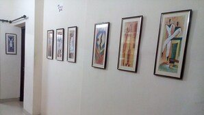 A hallway with six framed artworks on the wall. - Jo Rooms (Bidhannagar)