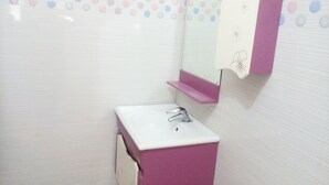 A bathroom with a white sink, a mirror, and a pink shelf. - Jo Rooms (Bidhannagar)