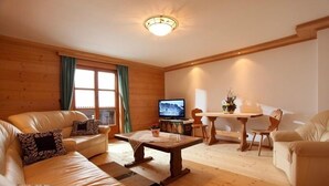 A cozy living room with a sofa set, a coffee table, a TV, and a dining area with a table and chairs.