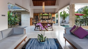 Un espacio habitable amplio con una mesa de comedor, sofás y una orquídea en el centro.