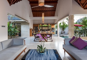 Relax in this stylish living area with a high ceiling, dining table, and comfortable sofa.