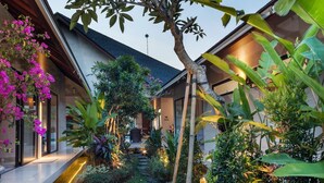 Una casa moderna con jardín que incluye una fuente, piedras para pisar y diversas plantas.