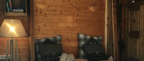 Ein Schlafzimmer einer Holzhütte mit einem Bett, Kissen, einer Lampe und einem Bücherregal.